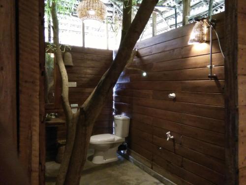 a bathroom with a tree next to a toilet at Cinnabar Resort in Tangalle