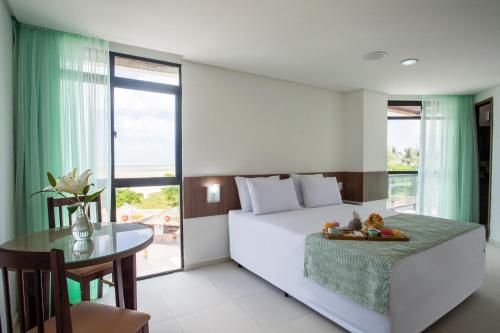 a bedroom with a bed and a table and a window at João Pessoa Hplus Beach in João Pessoa