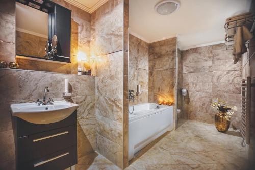 a bathroom with a tub, sink, mirror and bathtub at Komló Hotel Gyula in Gyula