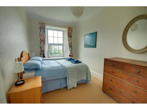 a bedroom with a bed and a window and a dresser at Old Vicarage Mortehoe in Mortehoe