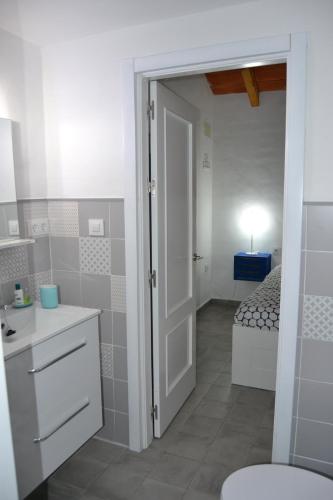 - Baño con puerta que da a un dormitorio con cama en Casa-Estudio Pachamama, en Zahora