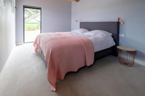 a bedroom with a bed with a pink blanket at B&B Erve ten Dam in Ambt Delden