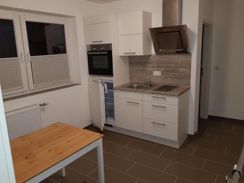 a kitchen with white cabinets and a sink and a microwave at FeWo Lena in Kinderbeuern