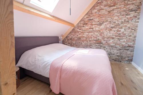 a bed in a room with a brick wall at B&B Erve ten Dam in Ambt Delden