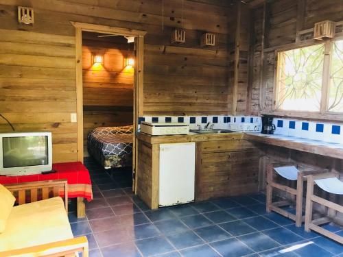 a kitchen in a log cabin with a bed at Roatan Bed & Breakfast Apartments in West End