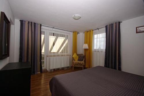 a bedroom with a bed and a chair and windows at Cozy Gardens Apartments in Prague in Prague