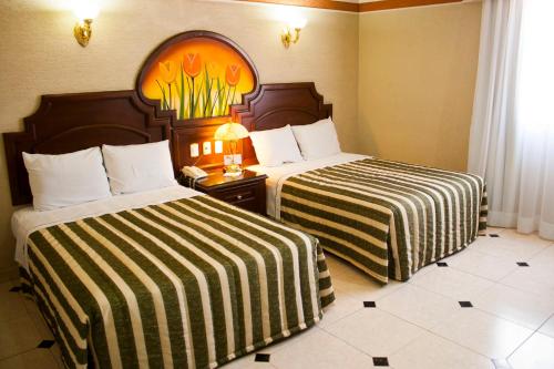 a hotel room with two beds with striped sheets at Hotel Casino Plaza in Guadalajara