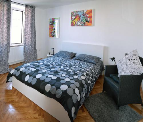 a bedroom with a black and white bed and a chair at Heart of the city app in Rijeka