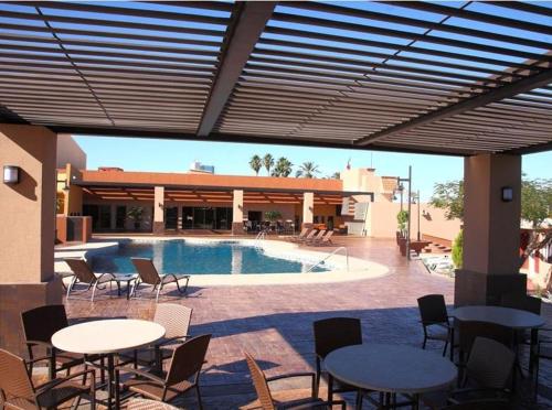 a patio with tables and chairs next to a pool at Hotel Gandara in Hermosillo