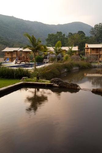 a body of water with houses and palm trees at Pousada Cantagalo in Itaipava