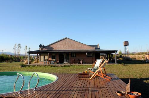 una terraza de madera con piscina y una casa en Refugio Del Guira Guira en Los Reartes