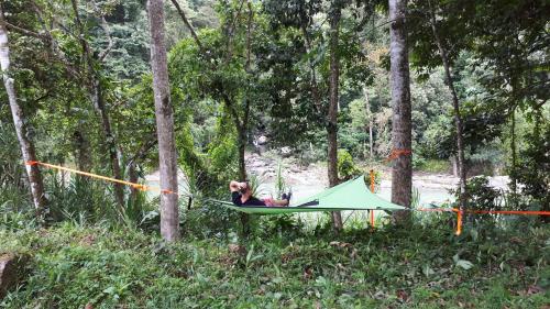 a person laying in a hammock in a forest at Finca Tres Equis - Farm and Forest in Tres Equis