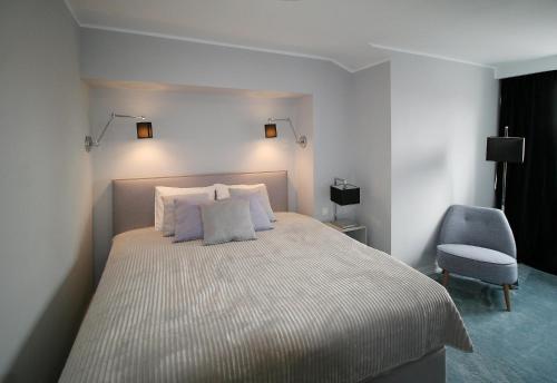 a bedroom with a large bed with a chair and lights at Apartament Mozart in Gdańsk
