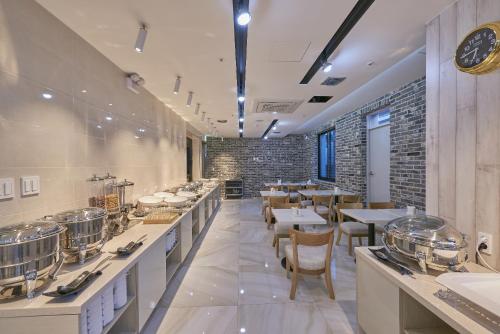 ein Restaurant mit Tischen und Stühlen und einer Uhr an der Wand in der Unterkunft Dubai Hotel in Gwangju