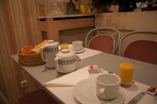 - une table avec un petit-déjeuner composé de café et de jus d'orange dans l'établissement Hôtel des Pyrénées - Entre Bastille et Nation, à Paris