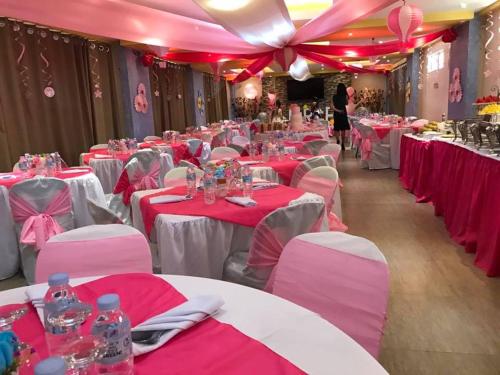 a room filled with tables with pink and white tablecloths at Royal Mansion Hotel in Tabaco