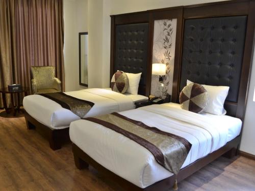 a hotel room with two beds and a chair at CityBay Palace Hạ Long Hotel in Ha Long