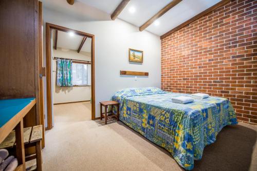 1 dormitorio con cama y pared de ladrillo en Evedon Lakeside Retreat, en Burekup