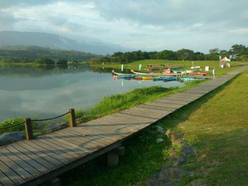 a wooden walkway next to a body of water with boats at 池上5159懷舊民宿 請勿用阿勾達訂房 in Chishang