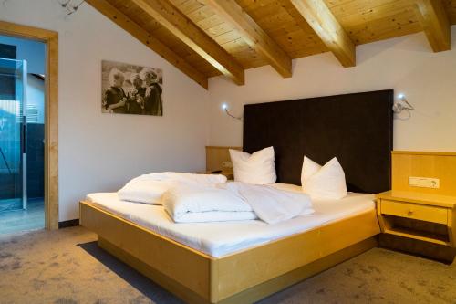 ein Schlafzimmer mit einem großen Bett mit weißer Bettwäsche und Kissen in der Unterkunft Apart Haus Bernardes in Fiss