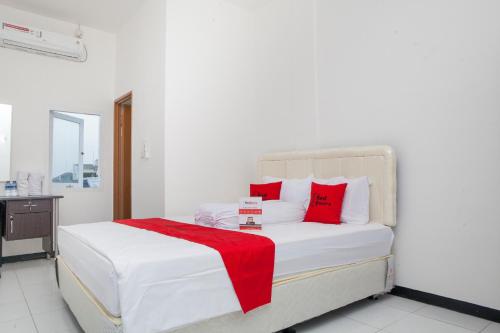ein weißes Bett mit roten Kissen in einem Zimmer in der Unterkunft RedDoorz near Telkom Corporate University in Bandung