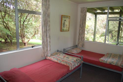 two beds in a room with two windows at Egmont Eco Leisure Park & Backpackers in New Plymouth