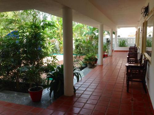 a porch with potted plants and tables and chairs at Meya Beach Walk Hotel in Mahabalipuram