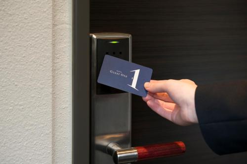 a person holding a card in front of a door at HOTEL Guest1 Ueno Ekimae in Tokyo