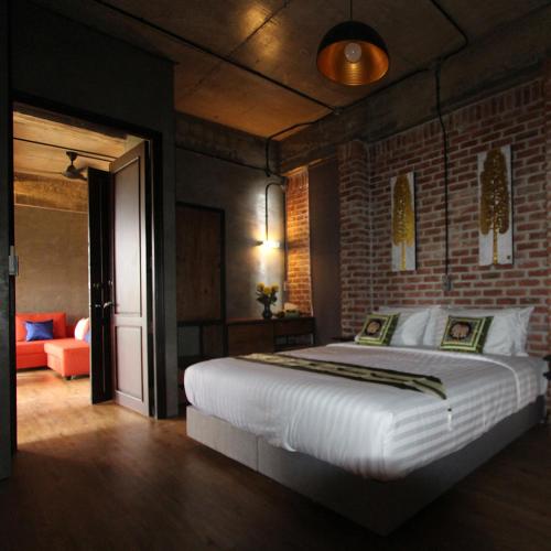 a bedroom with a large bed and a brick wall at Goodhope Villa in Sam Roi Yot