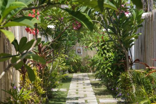 un sentiero nel giardino attraverso una recinzione con piante di Villas Edenia a Gili Trawangan