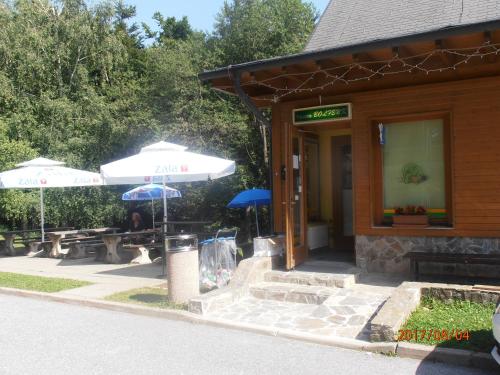 a restaurant with tables and umbrellas in front of it at Apartment Bolfenk in Pohorje