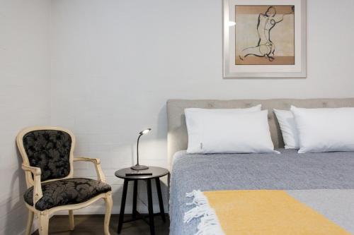 a bedroom with a bed and a chair and a table at Stay Fresh - Fremantle CBD in Fremantle