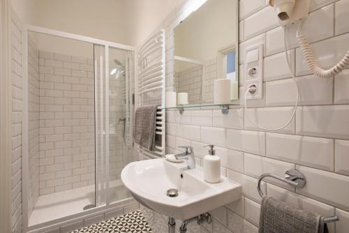 a white bathroom with a sink and a shower at Engel Apartman in Budapest