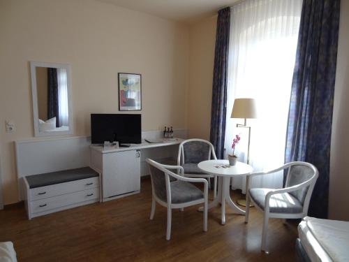 a room with a table and chairs and a television at Hotel Elisenhof in Chemnitz