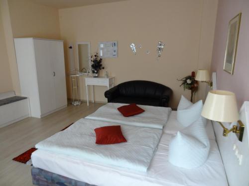 a large white bed with two red pillows on it at Hotel Elisenhof in Chemnitz