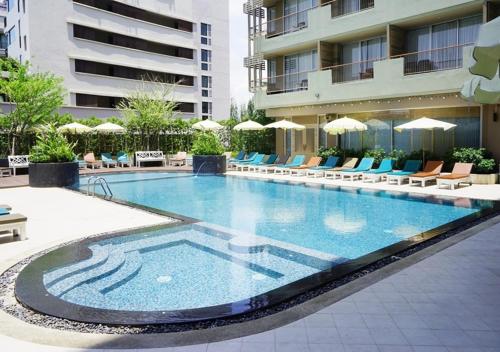 een groot zwembad met stoelen en een gebouw bij Long Beach Cha-Am Hotel in Cha Am