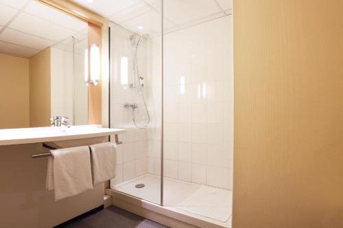a bathroom with a shower and a sink and a glass shower door at ibis Charleville Mézières in Villers-Semeuse