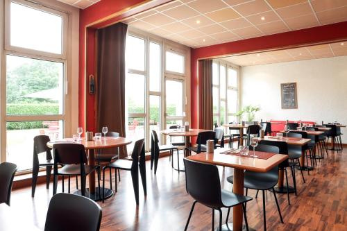 a dining room with tables and chairs and windows at ibis Charleville Mézières in Villers-Semeuse