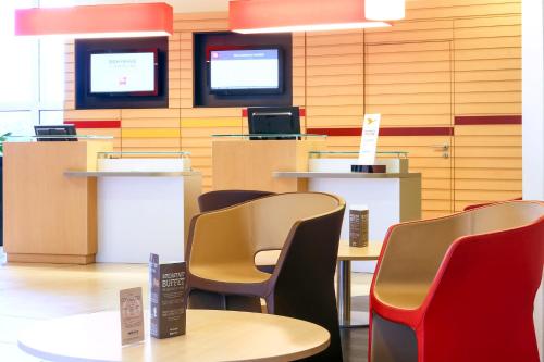 a waiting room with tables and chairs and televisions at ibis Charleville Mézières in Villers-Semeuse