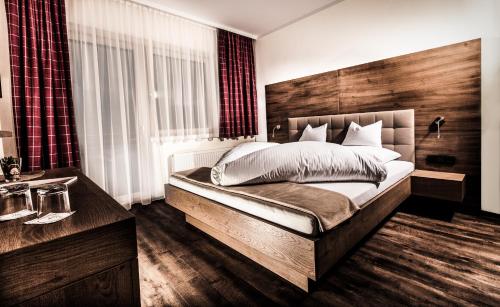 a bedroom with a large bed with a wooden headboard at Aktivhotel Tuxerhof in Zell am Ziller