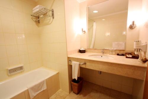 uma casa de banho com um lavatório, uma banheira e um espelho. em Harmoni Suites Hotel em Nagoya