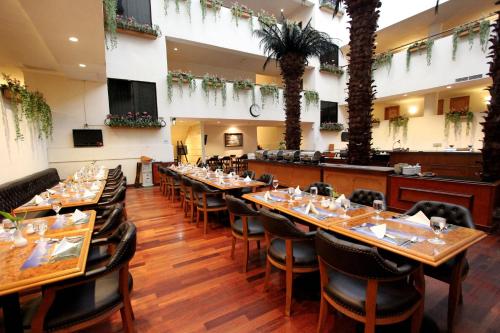 Un comedor con mesas largas y sillas. en Harmoni Suites Hotel, en Nagoya