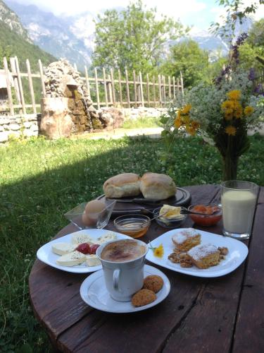 a wooden table with plates of food and cups of coffee at Shpella Guesthouse Theth in Theth