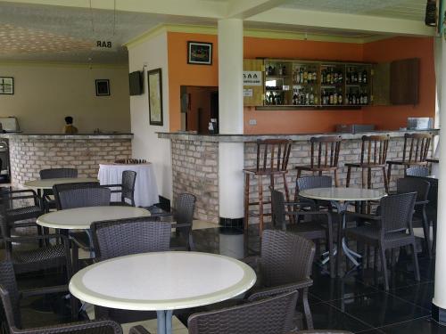 a restaurant with tables and chairs and a bar at The Crested Crane Bwindi Hotel in Rugando