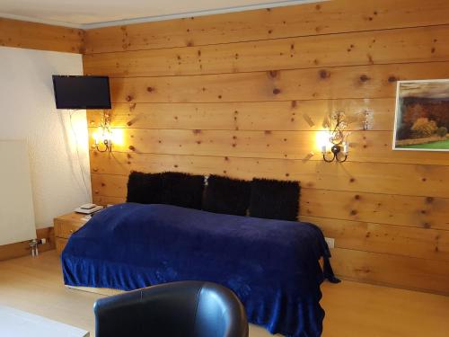 ein Schlafzimmer mit einer Holzwand mit einem Bett und einem Stuhl in der Unterkunft Appartement - Bristol Hôtel in Villars-sur-Ollon