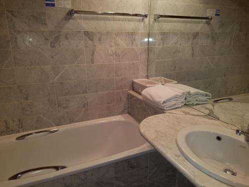 ein Badezimmer mit einer Badewanne und einem Waschbecken in der Unterkunft Appartement - Bristol Hôtel in Villars-sur-Ollon