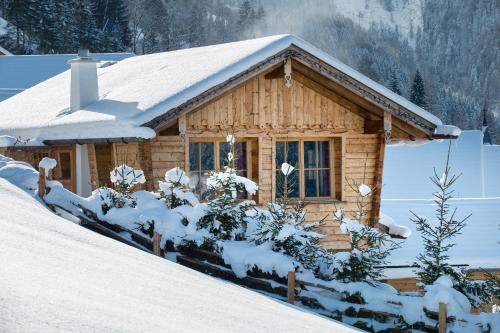 a log cabin with snow on the roof at Chaletdorf BERGHERZ in Sankt Johann im Pongau
