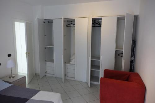 Un dormitorio con armarios blancos y una silla roja. en Casa Solemare, en Diano Marina