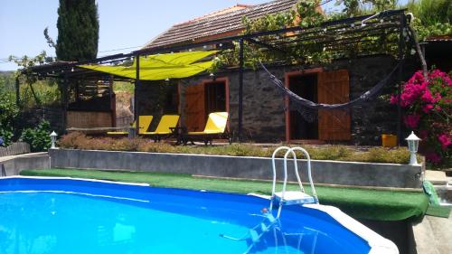 a house with a swimming pool in front of a house at Ocean View Cottage in Arco da Calheta