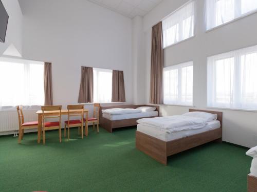 a room with two beds and a table and chairs at Win Budget B&B in Wiener Neustadt